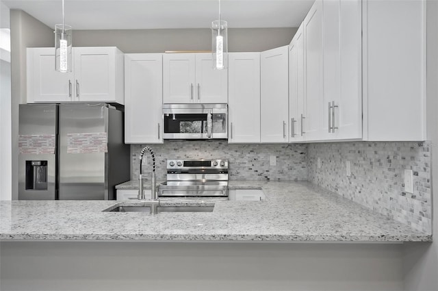 kitchen featuring light stone countertops, tasteful backsplash, stainless steel appliances, decorative light fixtures, and white cabinets