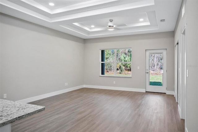 spare room with a raised ceiling, ceiling fan, and wood-type flooring