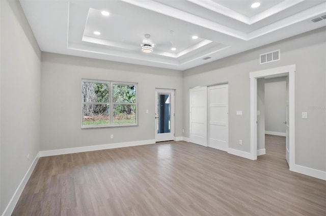 unfurnished bedroom featuring hardwood / wood-style floors and a tray ceiling