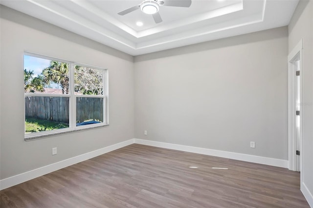 spare room featuring hardwood / wood-style floors, ceiling fan, and a raised ceiling