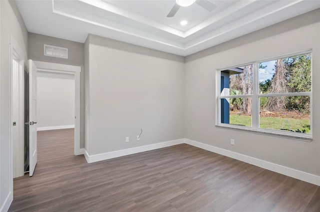 spare room with ceiling fan, dark hardwood / wood-style flooring, and a tray ceiling