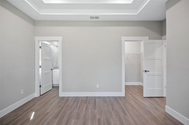 unfurnished bedroom featuring a closet, connected bathroom, a spacious closet, and light hardwood / wood-style flooring