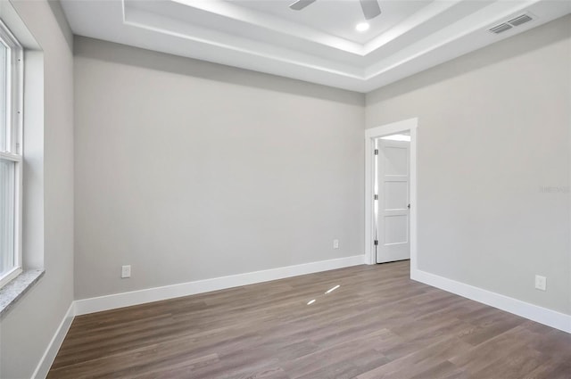 unfurnished room featuring ceiling fan, wood-type flooring, and a tray ceiling