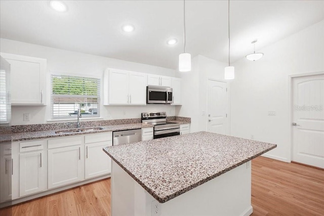 kitchen featuring white cabinets, stainless steel appliances, a kitchen island, and sink