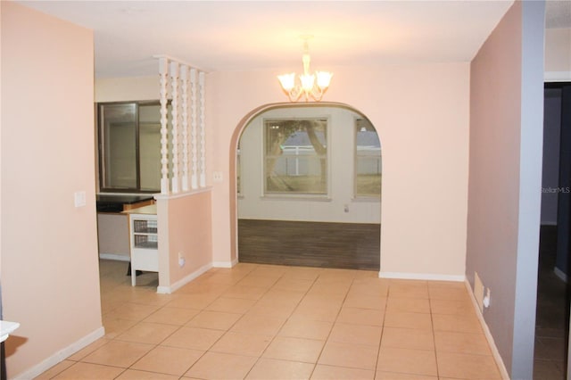 hall with light tile patterned floors and an inviting chandelier