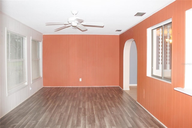 spare room with hardwood / wood-style flooring, ceiling fan, and wood walls