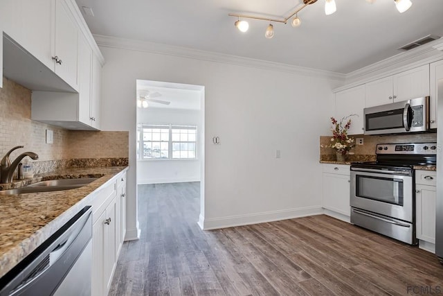 kitchen featuring sink, tasteful backsplash, hardwood / wood-style floors, white cabinets, and appliances with stainless steel finishes