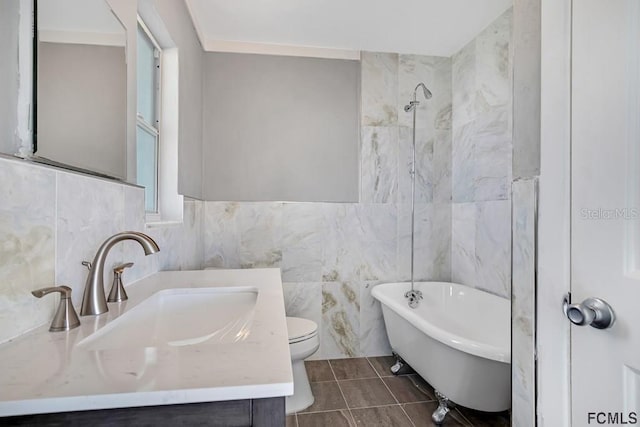 bathroom featuring vanity, tile patterned floors, a washtub, toilet, and tile walls