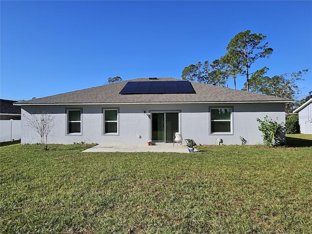 rear view of house with a patio area, a yard, and solar panels