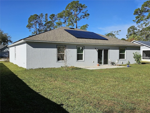 back of property with a lawn, solar panels, and a patio