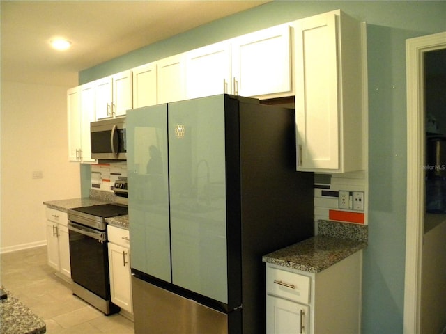 kitchen with tasteful backsplash, white cabinets, dark stone counters, and appliances with stainless steel finishes