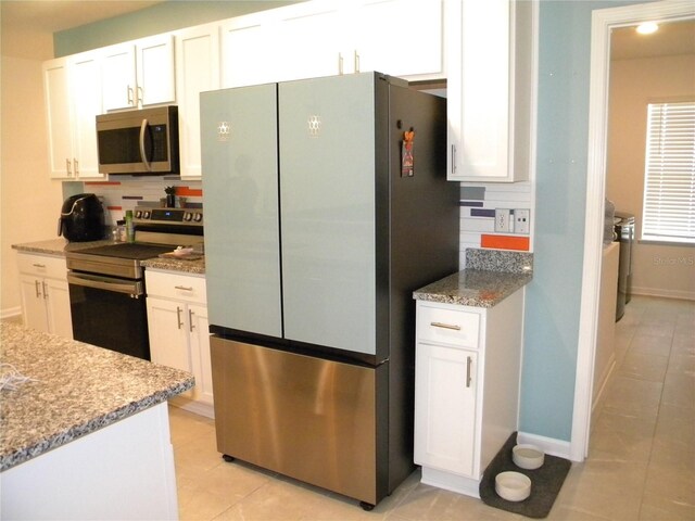 kitchen with light stone countertops, appliances with stainless steel finishes, tasteful backsplash, and white cabinetry
