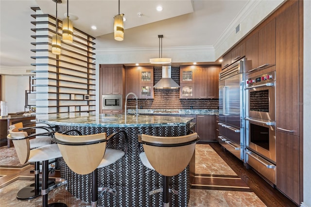 kitchen featuring crown molding, pendant lighting, wall chimney range hood, and appliances with stainless steel finishes