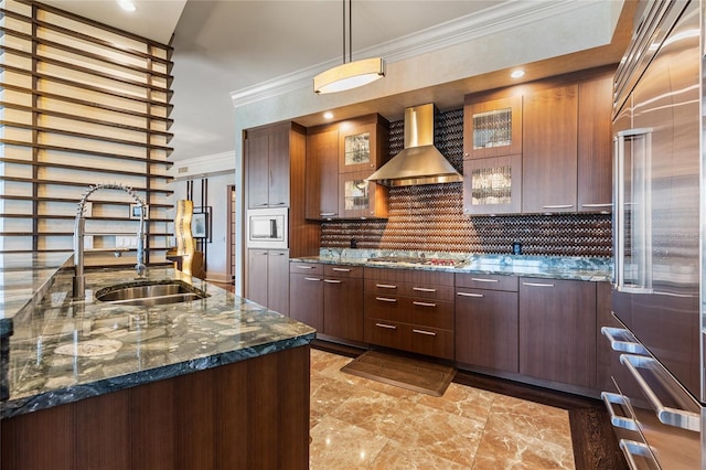 kitchen featuring pendant lighting, built in appliances, crown molding, and wall chimney range hood