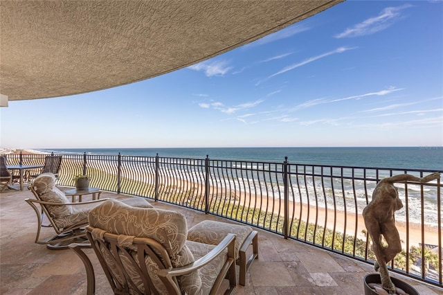 balcony featuring a view of the beach and a water view