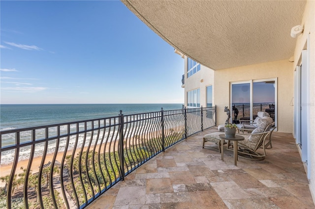 balcony featuring a view of the beach and a water view