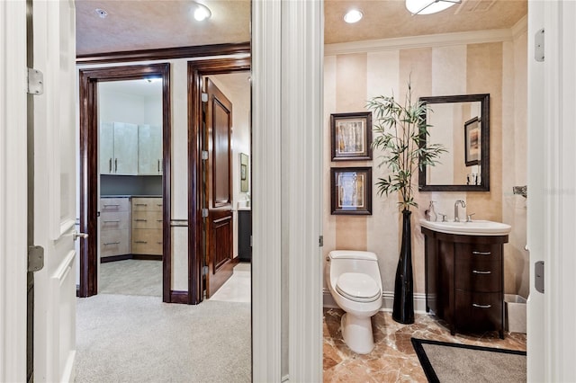 bathroom featuring toilet, vanity, and ornamental molding