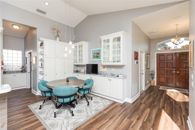 dining space with dark hardwood / wood-style floors, high vaulted ceiling, and a chandelier