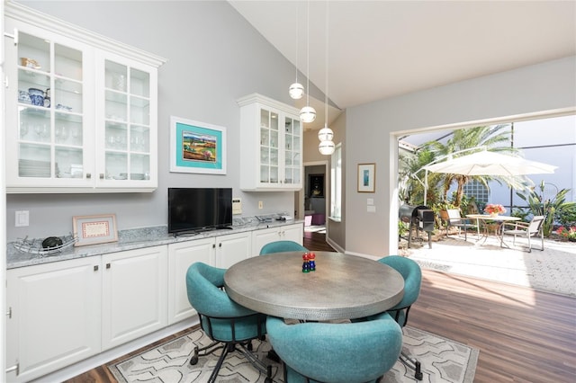 dining area with high vaulted ceiling and wood-type flooring