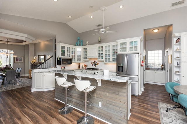 kitchen featuring white cabinetry, light stone countertops, stainless steel refrigerator with ice dispenser, a kitchen island, and ceiling fan with notable chandelier