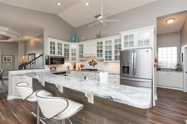 kitchen with white cabinets, custom exhaust hood, light stone countertops, and appliances with stainless steel finishes