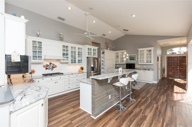 kitchen featuring light stone countertops, white cabinetry, tasteful backsplash, appliances with stainless steel finishes, and custom exhaust hood