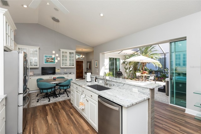 kitchen with stainless steel appliances, vaulted ceiling, sink, a center island with sink, and white cabinetry