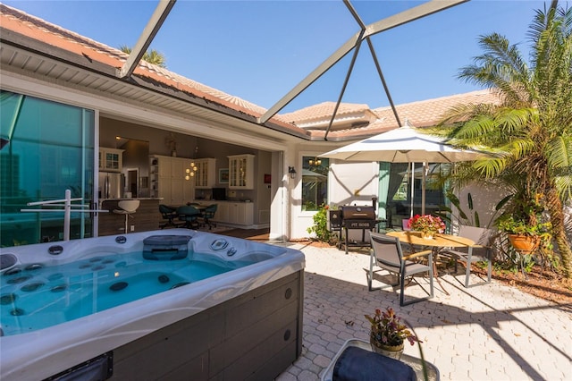 view of patio / terrace featuring a hot tub and a lanai