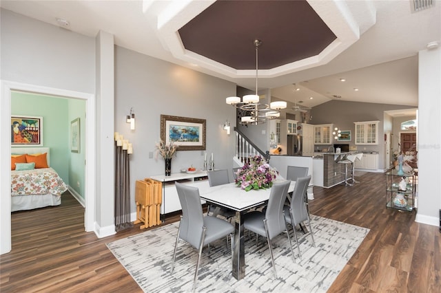 dining space with a raised ceiling, dark wood-type flooring, and a notable chandelier