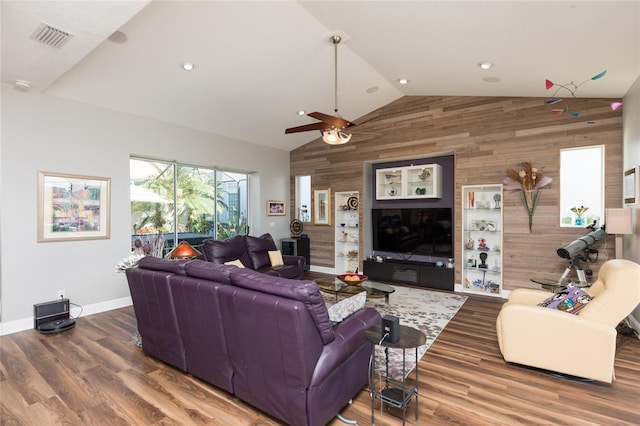 living room with hardwood / wood-style floors, ceiling fan, wooden walls, and vaulted ceiling