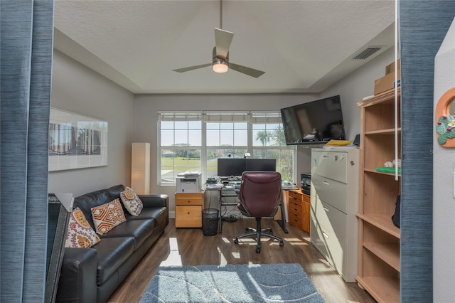 home office featuring a textured ceiling, dark hardwood / wood-style flooring, a raised ceiling, and ceiling fan