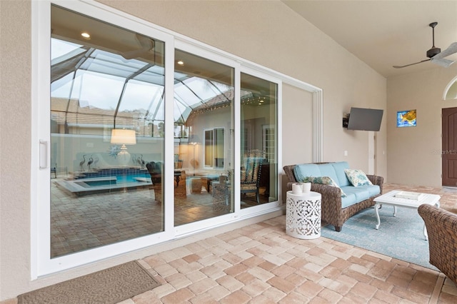 view of patio featuring glass enclosure, an outdoor living space, and ceiling fan