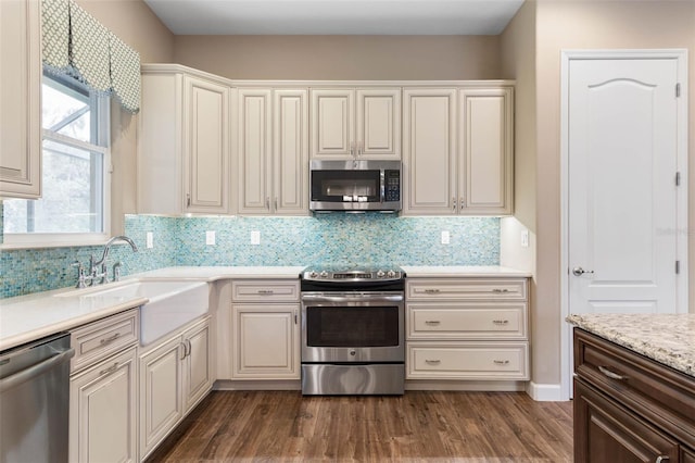 kitchen with dark hardwood / wood-style flooring, stainless steel appliances, tasteful backsplash, and sink