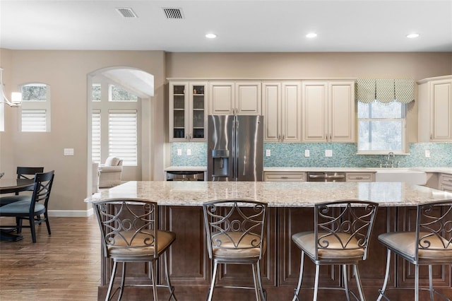 kitchen with a breakfast bar, sink, appliances with stainless steel finishes, a large island, and light stone counters