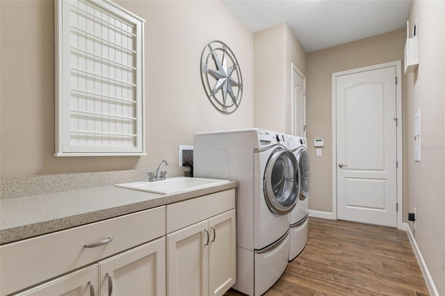 laundry area featuring sink, washer and dryer, and wood-type flooring