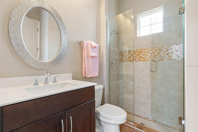 bathroom with an enclosed shower, vanity, and toilet