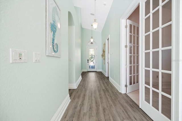 hallway with french doors, hardwood / wood-style flooring, and high vaulted ceiling