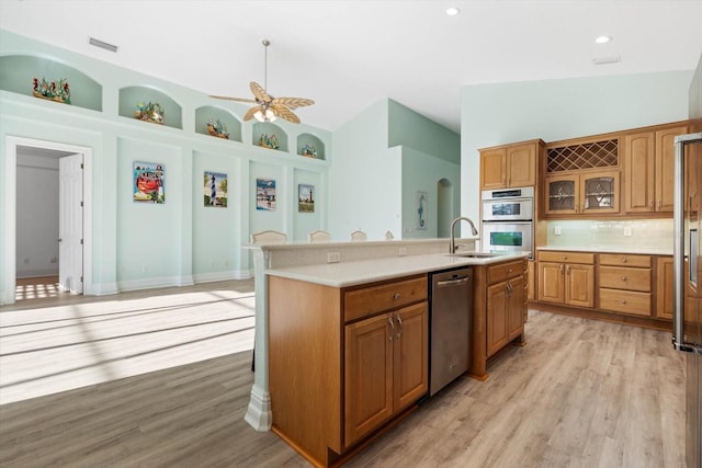 kitchen with sink, built in features, appliances with stainless steel finishes, tasteful backsplash, and a kitchen island