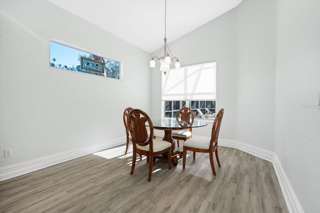 dining room with wood-type flooring, an inviting chandelier, and vaulted ceiling