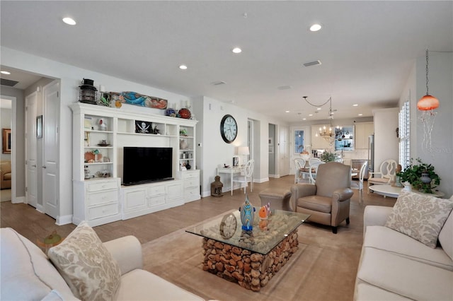 living room with light wood-type flooring and a notable chandelier