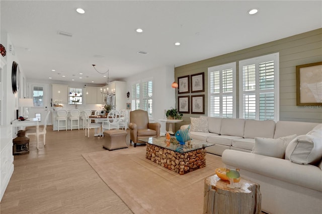 living room with light hardwood / wood-style floors and a notable chandelier