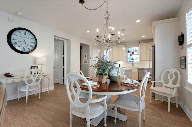 dining space with light hardwood / wood-style floors and an inviting chandelier