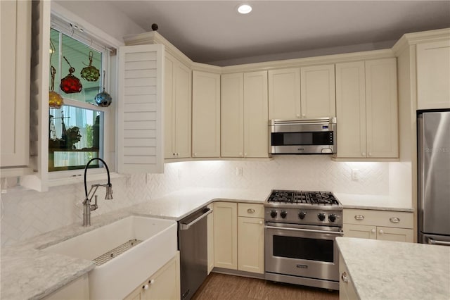 kitchen with decorative backsplash, sink, stainless steel appliances, and cream cabinetry