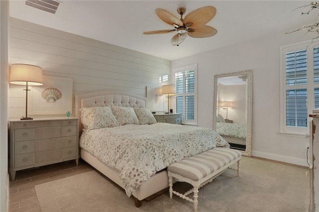 bedroom with ceiling fan and wood walls