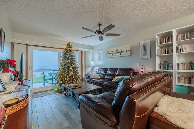 living room with hardwood / wood-style flooring, ceiling fan, and a textured ceiling