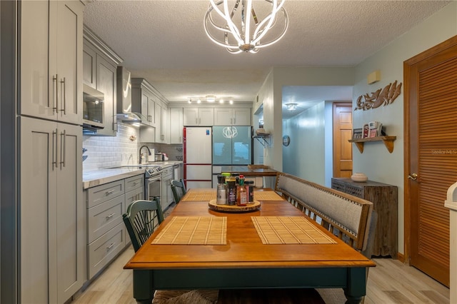 dining space with light hardwood / wood-style floors, a textured ceiling, and an inviting chandelier