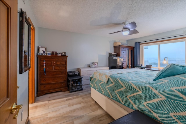 bedroom with ceiling fan, light hardwood / wood-style floors, and a textured ceiling