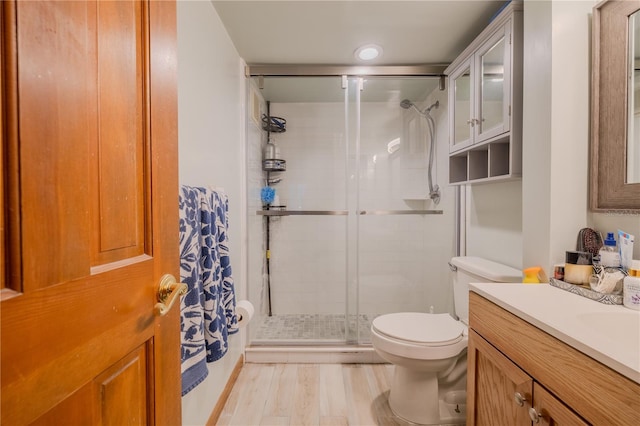 bathroom featuring hardwood / wood-style floors, vanity, an enclosed shower, and toilet