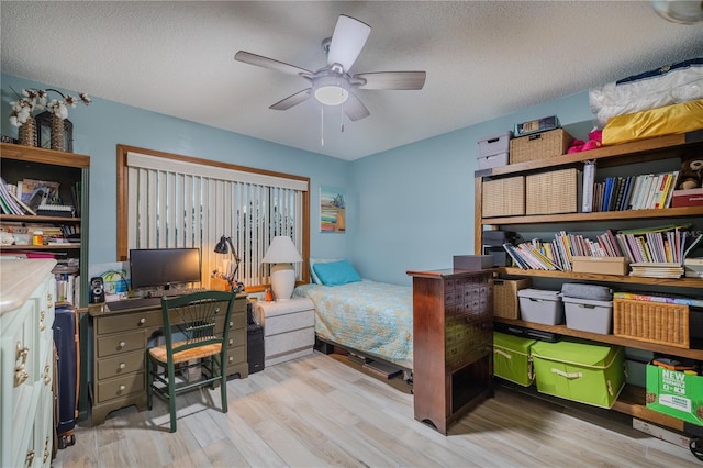 bedroom featuring ceiling fan, light wood-type flooring, and a textured ceiling