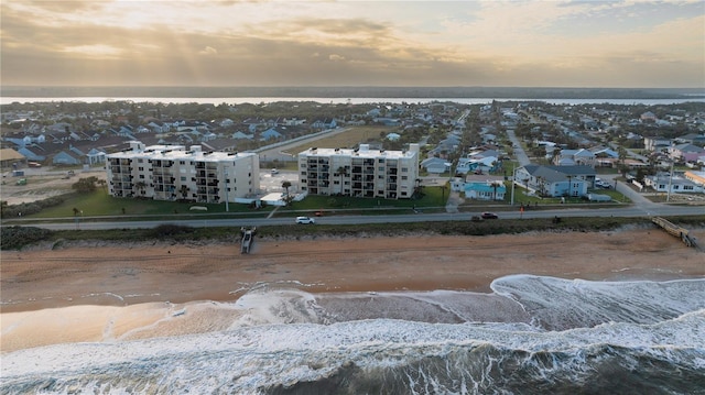 aerial view at dusk with a view of the beach and a water view